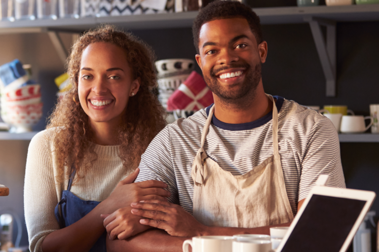 Two small-business owners smiling. Read about Minnesota work comp law for small businesses.