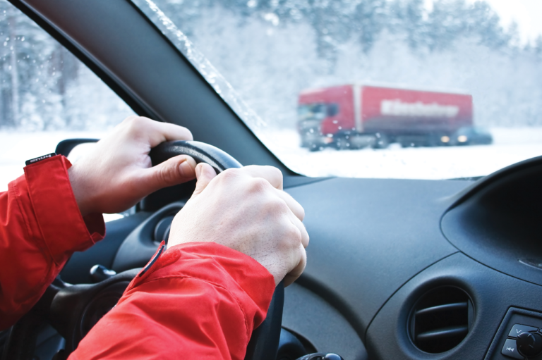 A person riving in winter. Learn about safety tips for winter driving.