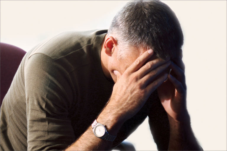 A man with his head in his hands. Read about preventing depression among workers.