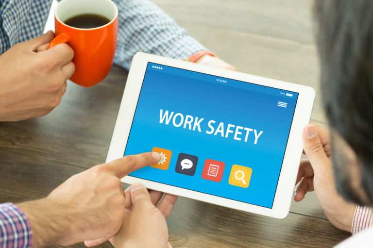 Employees pointing to a tablet that says "work safety." Learn about whether employees are compensated when injured while violating company rules.
