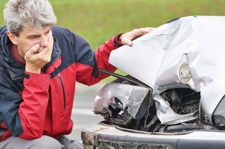 A man inspecting a car crash. Read about whether work comp insurance covers car accidents.