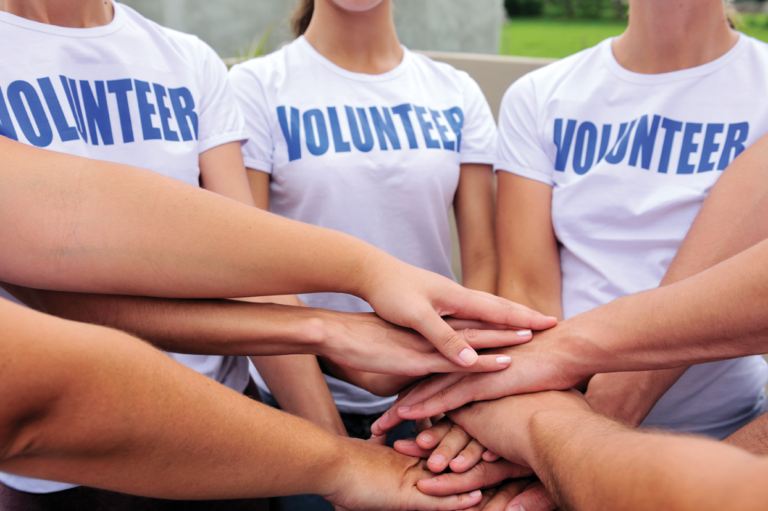 A group of volunteers with their hands together. Read about whether volunteers qualify for workers' compensation.