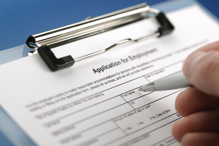 A person filling out a job application. Read about whether you can screen job applicants for prior workers' compensation claims.