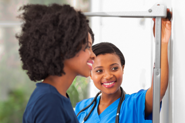 A health care worker checking the height of a patient. Read about workplace wellness.