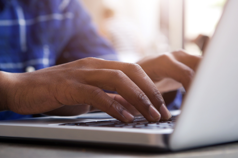 A person typing at a computer. Read about reporting injuries to OSHA versus your work comp insurer.