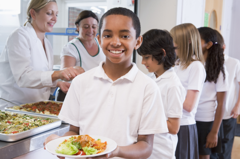 A school child getting lunch in line at a cafeteria. Read about work injuries among school employees.
