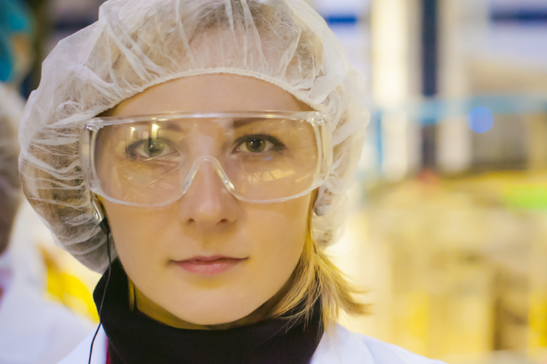 A worker with a hairnet and protective glasses. Read about liability limits.