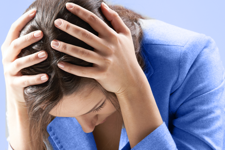 A stressed person with her hands on her head. Read about the issues with keeping problem employees on staff as it relates to work comp.