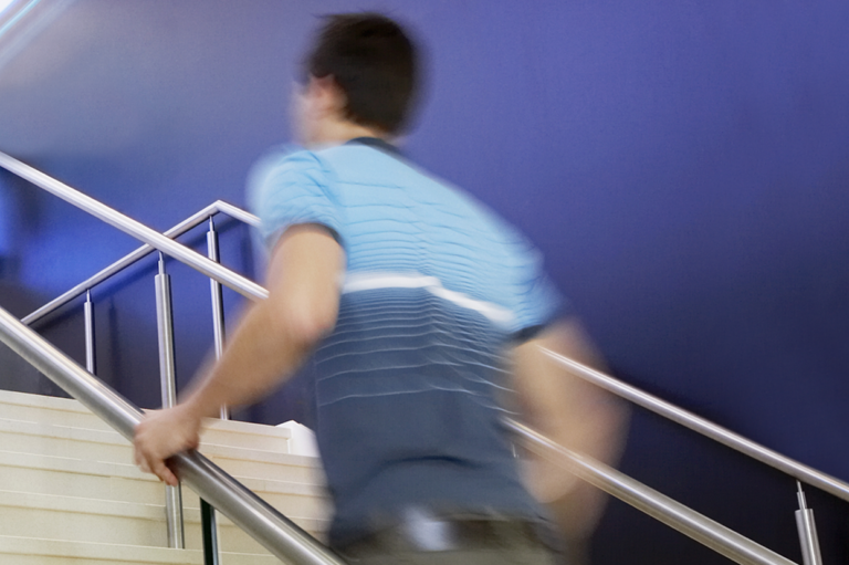 A blurred-out person going up the stairs. Read about using handrails.