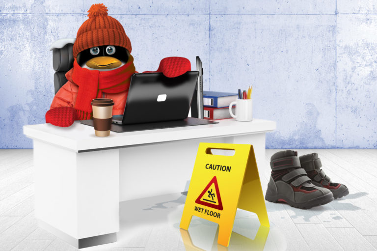 SFM penguin mascot at a desk with a wet floor warning sign. Learn how to winter-proof your workplace to prevent slips and falls.
