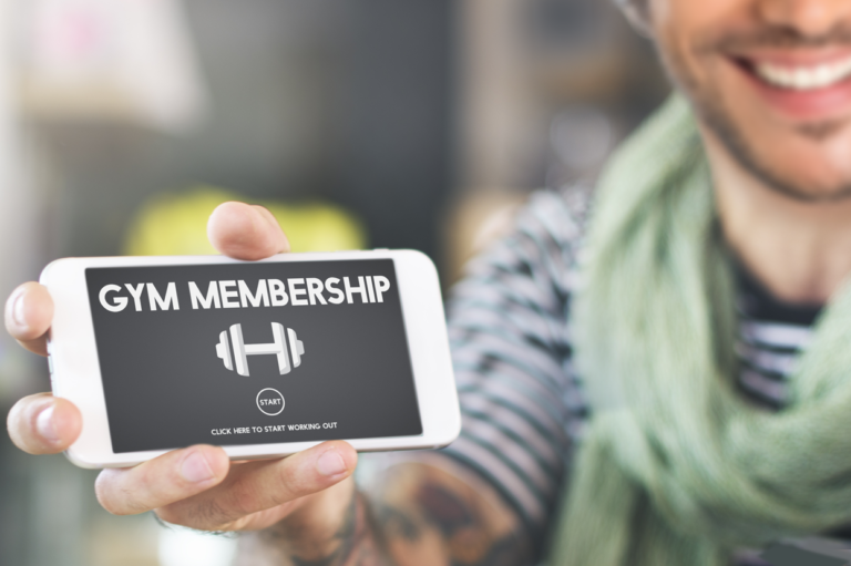 A person holding a phone that says "gym membership." Learn about wellness programs and best practices.