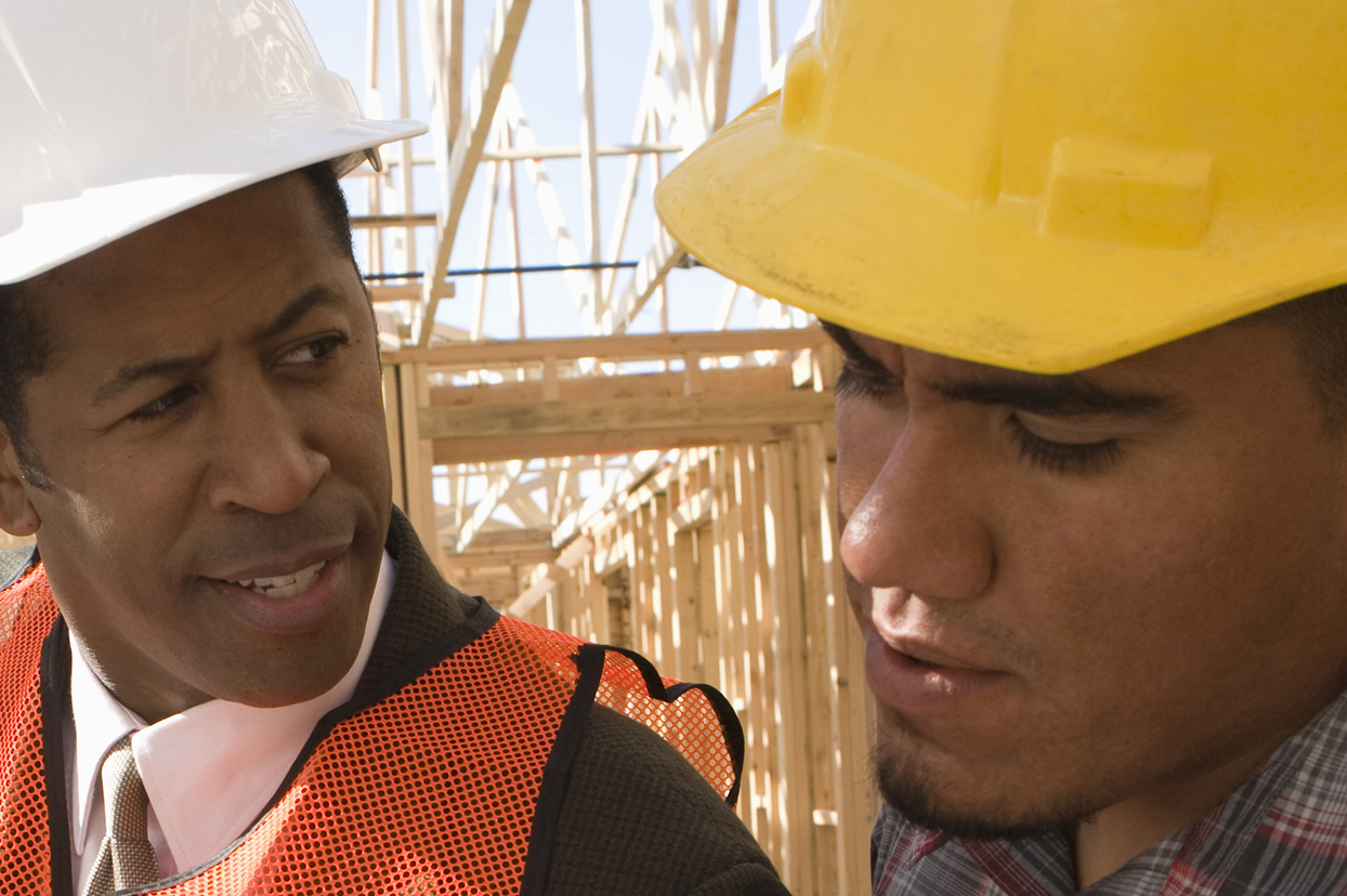 Two workers speaking at a construction site