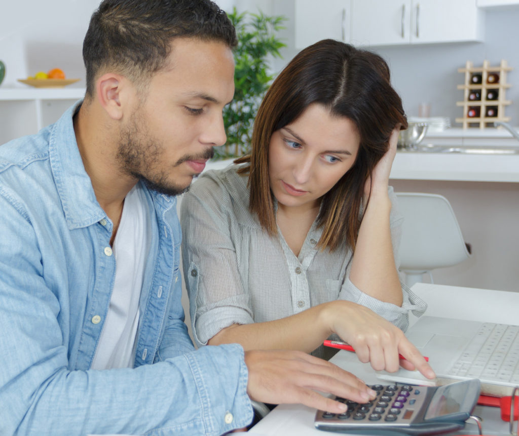 Two people  sitting together and using a calculator