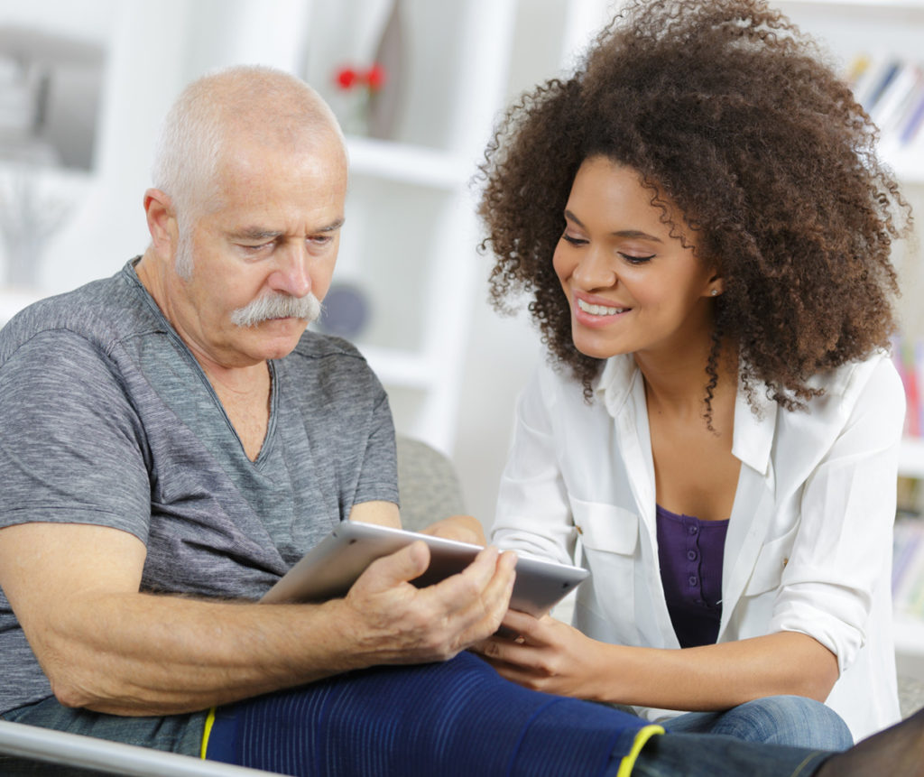 Woman sitting with an injured worker in a cast, helping him fill out paperwork